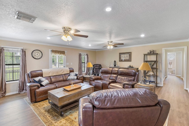 living area featuring a textured ceiling, visible vents, baseboards, and light wood-type flooring