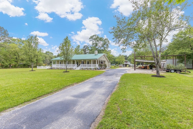 view of front facade featuring a carport, aphalt driveway, a chimney, covered porch, and a front lawn