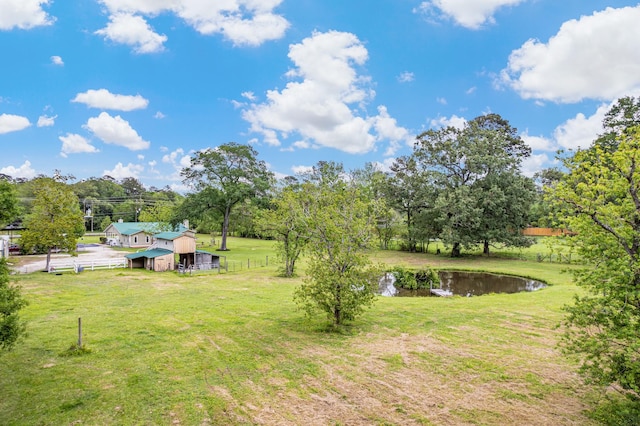 view of yard featuring an outdoor structure, a water view, a barn, and fence