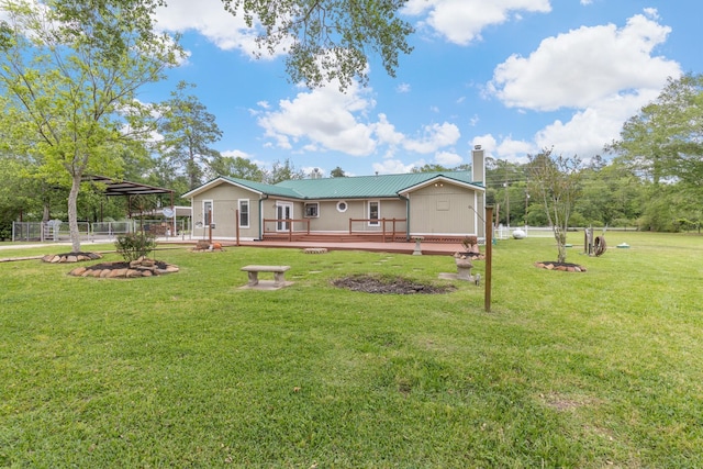 rear view of property featuring a deck, an outdoor fire pit, a chimney, fence, and a lawn
