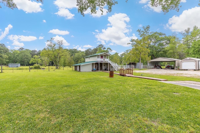 view of yard with fence, a carport, driveway, and an outdoor structure