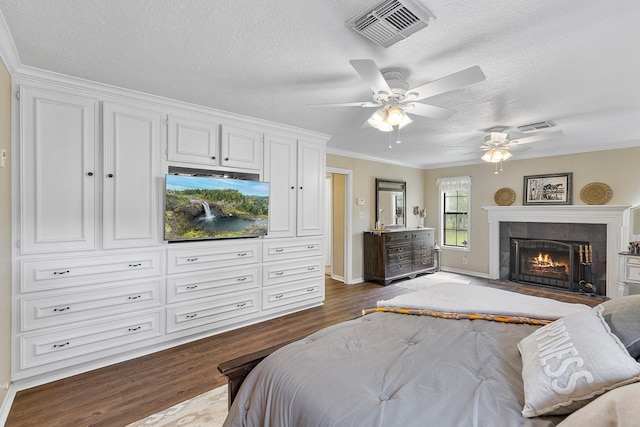 bedroom featuring visible vents, ornamental molding, a textured ceiling, and dark wood-style flooring