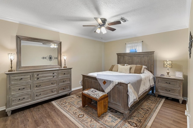bedroom with a textured ceiling, baseboards, ornamental molding, dark wood finished floors, and a ceiling fan