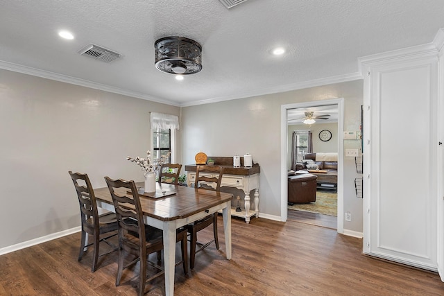 dining space featuring dark wood-style flooring, visible vents, and crown molding