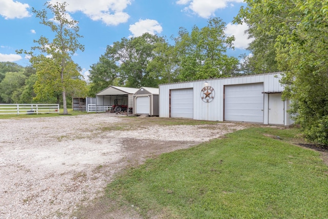 garage featuring a detached garage, fence, and driveway