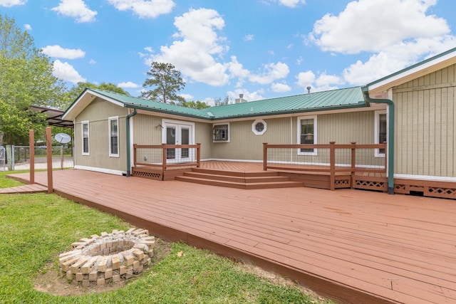 back of property featuring a lawn, a fire pit, french doors, and a wooden deck