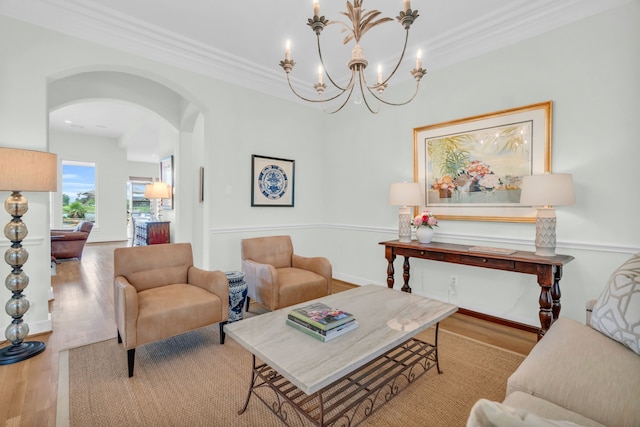 living area featuring wood finished floors, crown molding, a chandelier, and arched walkways