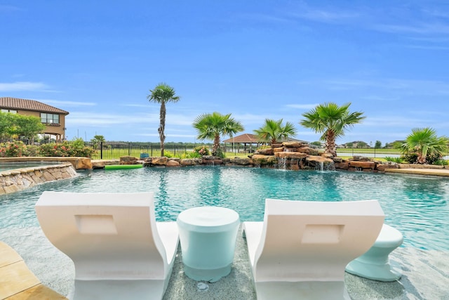 view of pool featuring fence and a pool with connected hot tub