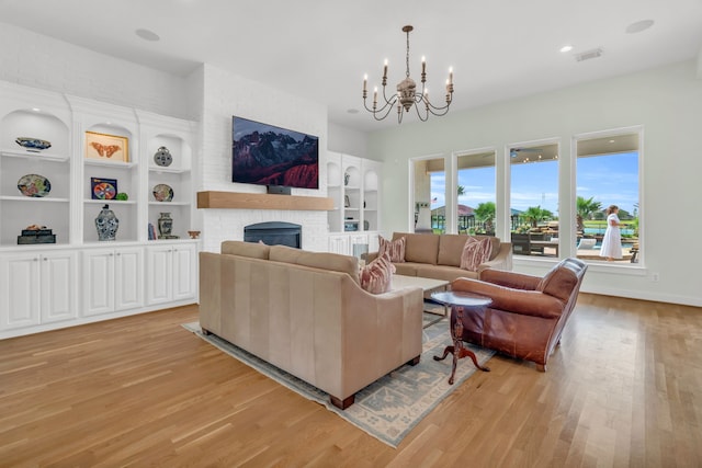 living room featuring light wood-style floors, visible vents, an inviting chandelier, a fireplace, and built in shelves
