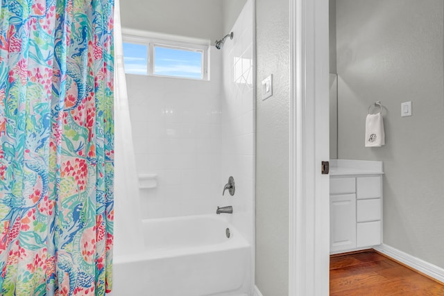 bathroom with wood finished floors, a textured wall, vanity, baseboards, and shower / tub combo with curtain