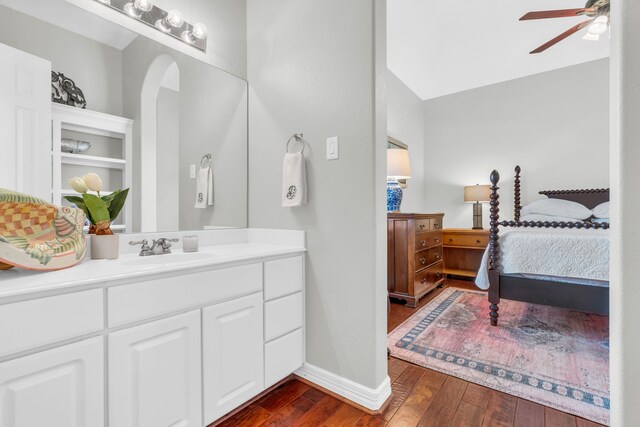 ensuite bathroom featuring hardwood / wood-style floors, ceiling fan, ensuite bathroom, vanity, and baseboards