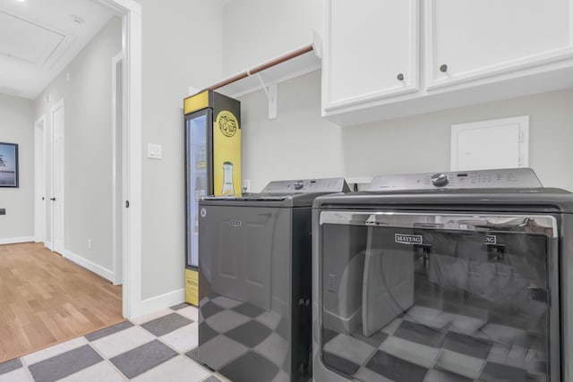 laundry room featuring baseboards, light floors, cabinet space, and independent washer and dryer