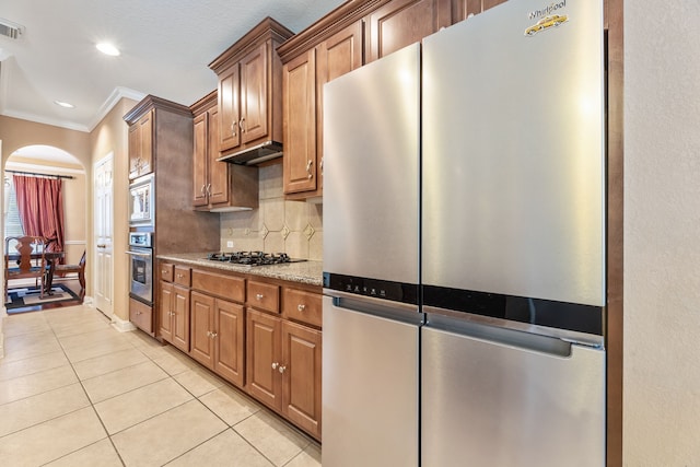 3719 Arundel Gardens Ln, Sugar Land, TX 77498 - kitchen with stainless steel appliances, crown molding, light tile patterned flooring, under cabinet range hood, and backsplash