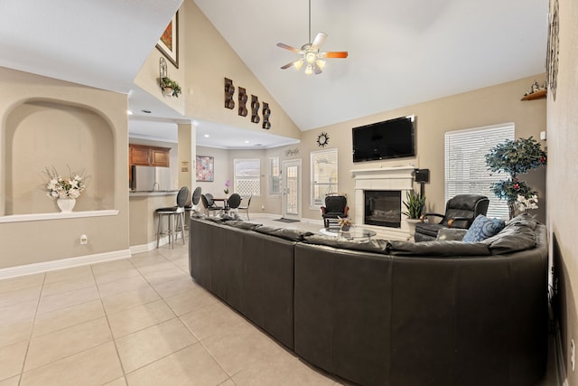 3719 Arundel Gardens Ln, Sugar Land, TX 77498 - living area with high vaulted ceiling, a glass covered fireplace, ceiling fan, light tile patterned floors, and baseboards