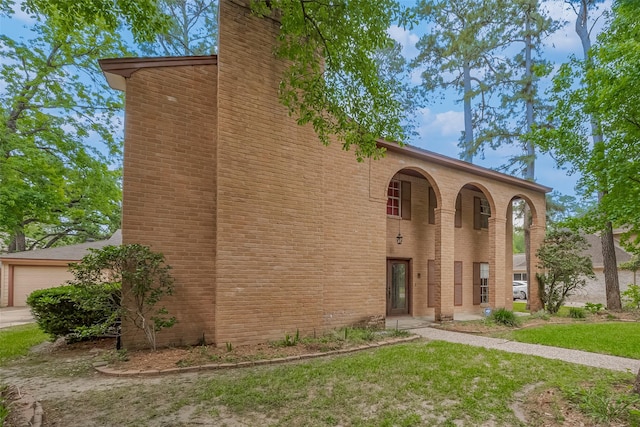 view of front of home featuring a chimney, brick siding, a front lawn, and an attached garage