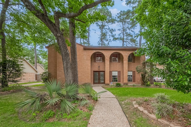 view of front facade with a front lawn, french doors, and brick siding