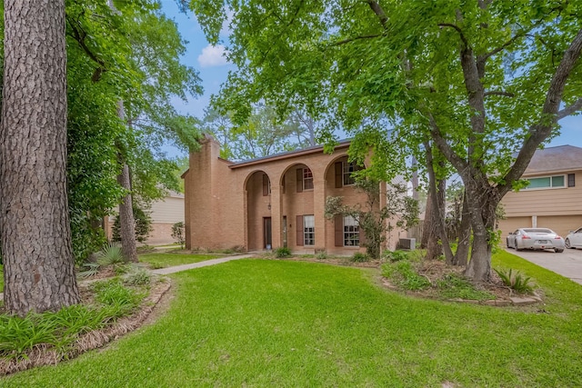 mediterranean / spanish-style house with a chimney, central AC, a front yard, and brick siding