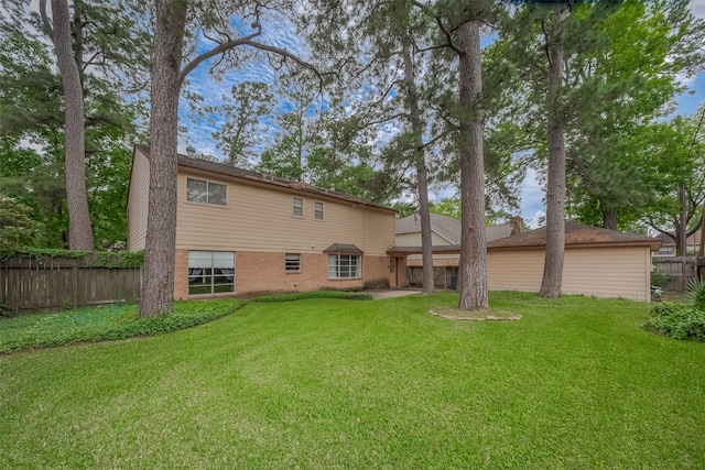 rear view of property featuring brick siding, fence, and a lawn