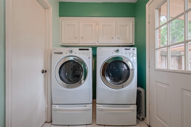 washroom with light tile patterned floors, washer and dryer, and cabinet space