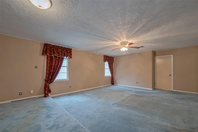 empty room featuring carpet flooring, a textured ceiling, a ceiling fan, and baseboards