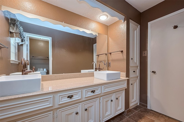 bathroom featuring double vanity, a sink, and a textured wall