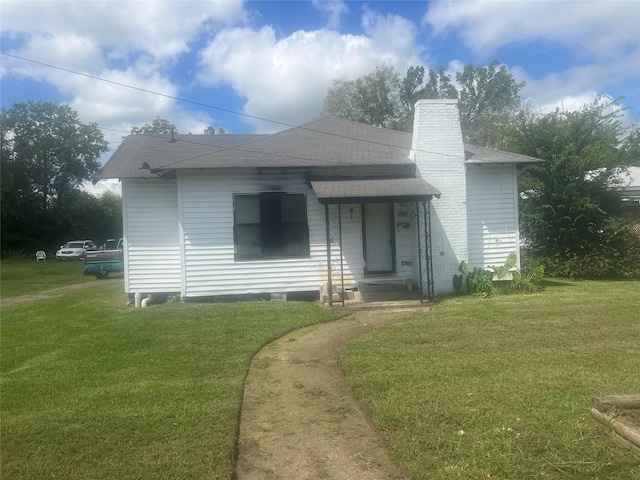 view of front of home featuring a front lawn, a chimney, and roof with shingles