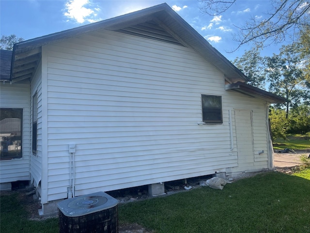 view of side of home with cooling unit and a lawn