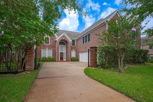 view of front of property with brick siding, fence, driveway, a front yard, and an attached garage