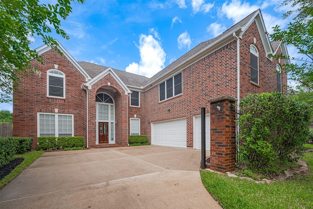 traditional home with driveway, roof with shingles, a garage, and brick siding