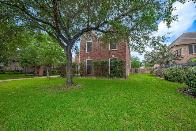 view of front of home with a front lawn, brick siding, and fence