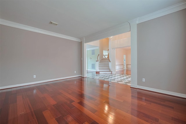 empty room with wood finished floors, stairway, baseboards, visible vents, and crown molding