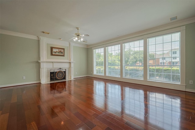 unfurnished living room with ornamental molding, a ceiling fan, wood finished floors, and baseboards