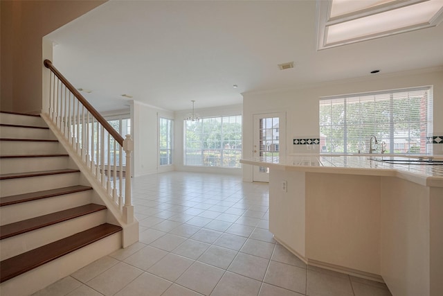 interior space featuring light tile patterned floors, crown molding, stovetop, visible vents, and a chandelier