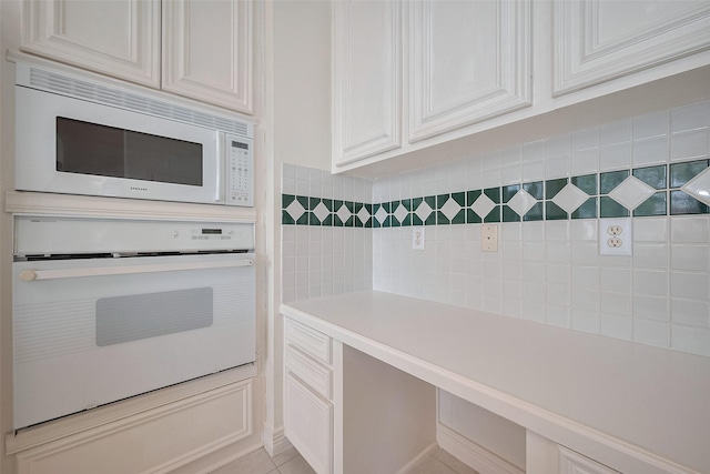 kitchen with light countertops, white cabinets, backsplash, and white appliances