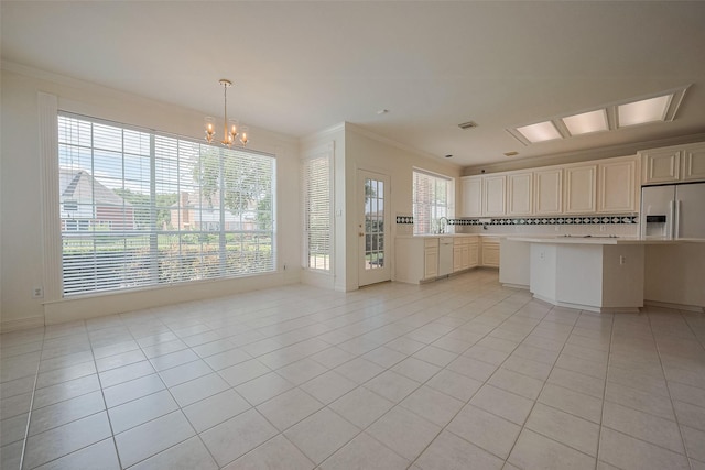 kitchen with tasteful backsplash, light countertops, ornamental molding, a notable chandelier, and light tile patterned flooring