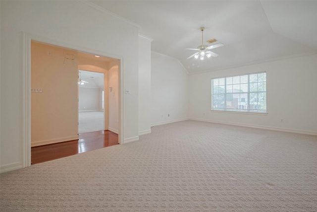 carpeted empty room featuring ceiling fan, ornamental molding, vaulted ceiling, and baseboards