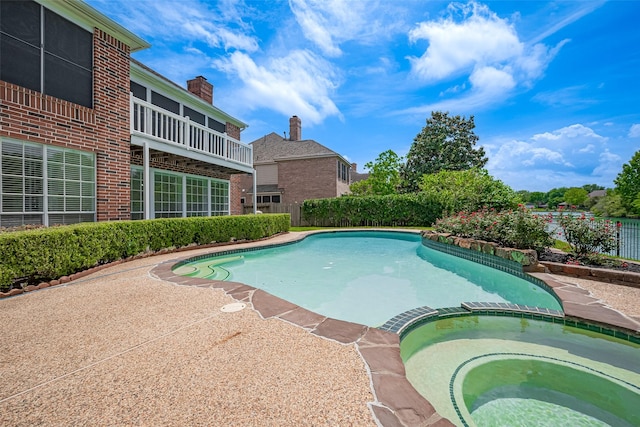 view of swimming pool featuring a pool with connected hot tub and fence