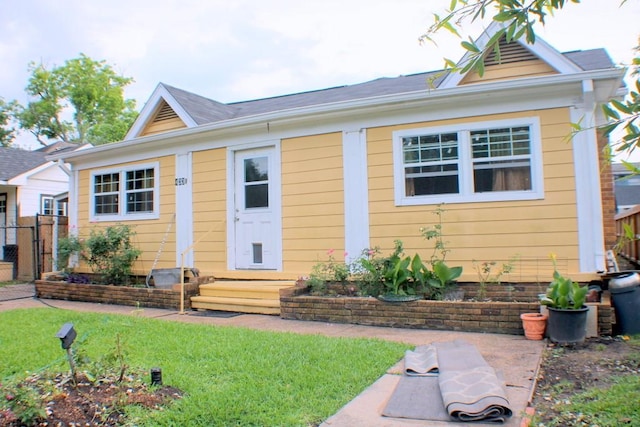 bungalow-style home with fence, entry steps, and a front yard