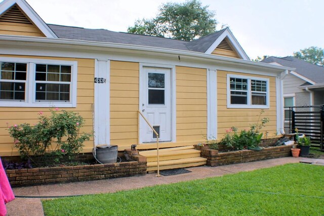 entrance to property featuring a lawn and fence