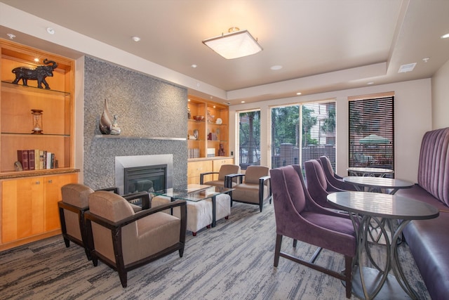 living room featuring visible vents, wood finished floors, a large fireplace, and built in features