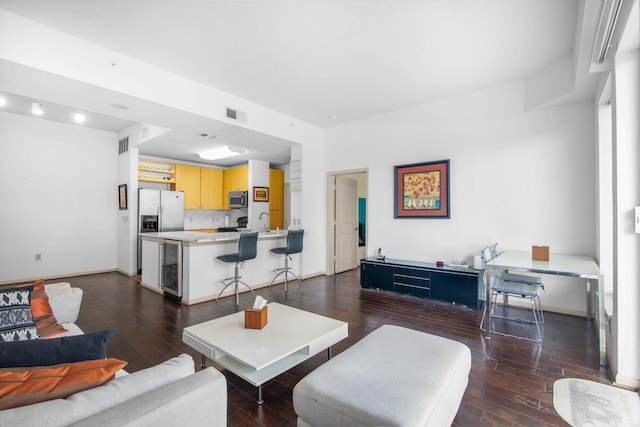 living room with dark wood-style floors, beverage cooler, visible vents, and baseboards