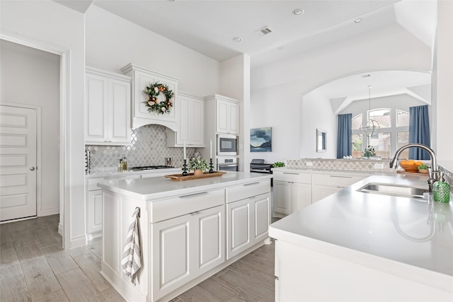 kitchen with arched walkways, light countertops, white cabinets, a sink, and built in microwave