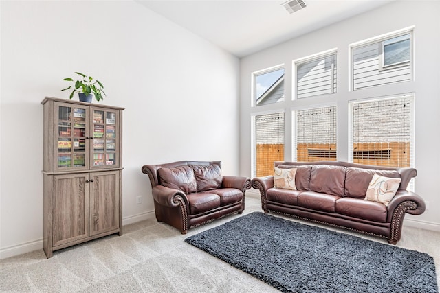 living room with light colored carpet, visible vents, a high ceiling, and baseboards