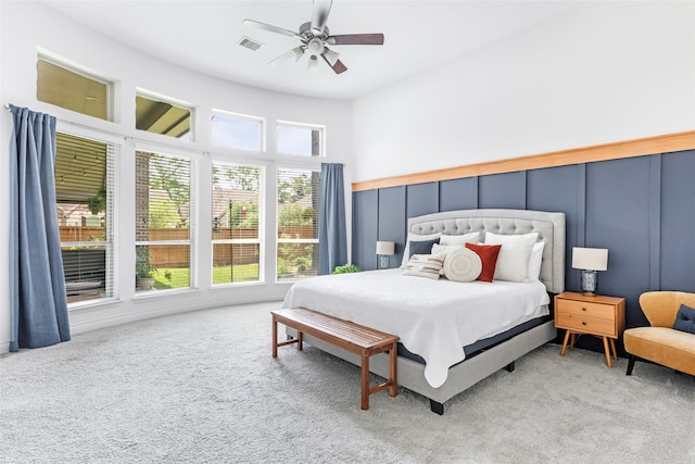 bedroom featuring a decorative wall, visible vents, ceiling fan, and carpet