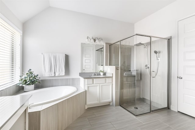 bathroom featuring a garden tub, a stall shower, vaulted ceiling, and vanity