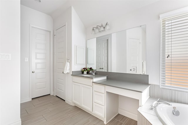 full bathroom featuring vanity, a relaxing tiled tub, and wood finished floors