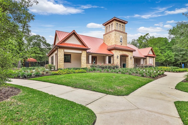 view of front of property featuring a standing seam roof, a front lawn, metal roof, stone siding, and stucco siding
