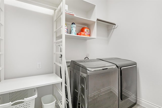 washroom featuring washing machine and dryer, laundry area, and baseboards