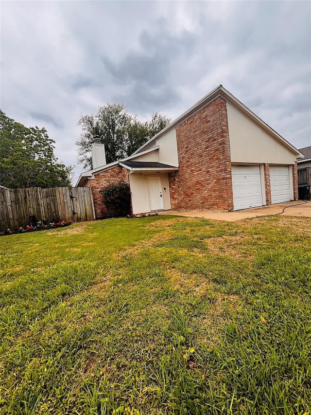 view of side of property featuring driveway, a chimney, fence, a yard, and brick siding