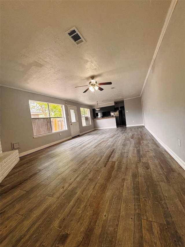 unfurnished living room featuring ceiling fan, dark wood-style flooring, baseboards, visible vents, and crown molding